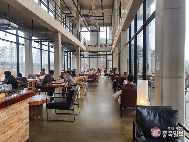 Intérieur lumineux d'un café coréen (Grownbean Coffee 그로우빈커피) sur deux niveaux, avec de grandes baies vitrées, des tables en bois et des clients installés individuellement