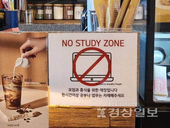 Panneau "No Study Zone" affiché dans un café coréen, avec un pictogramme d'ordinateur barré et un message en coréen demandant de ne pas étudier plus d'une heure.