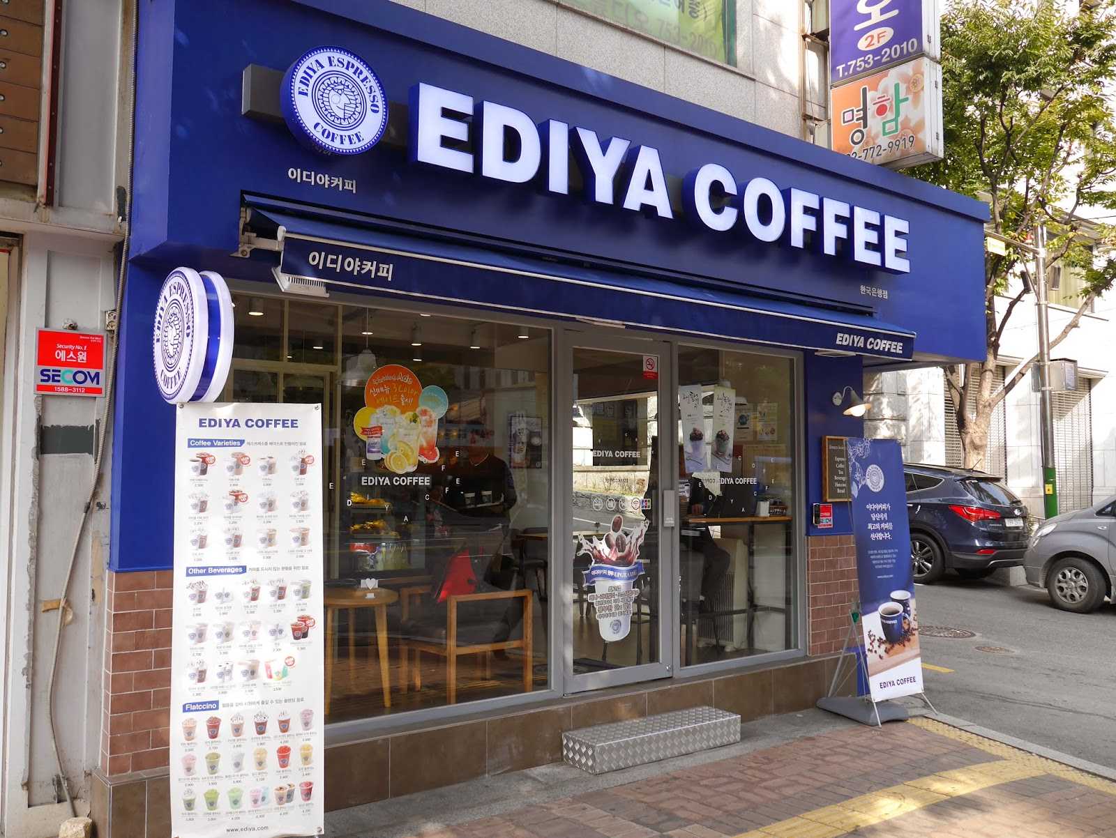 Façade bleue d'un café Ediya Coffee (이디야커피) dans une rue de Corée du Sud, avec un menu affiché sur un panneau à l'entrée.