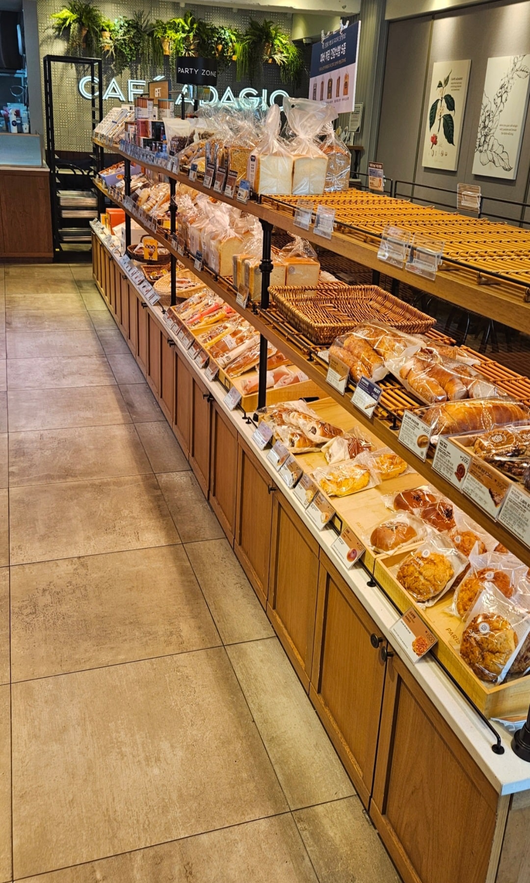 Rayons de viennoiseries et de pains emballés dans une boulangerie-café Paris Baguette en Corée du Sud, avec l'enseigne "Café Adagio" visible en arrière-plan