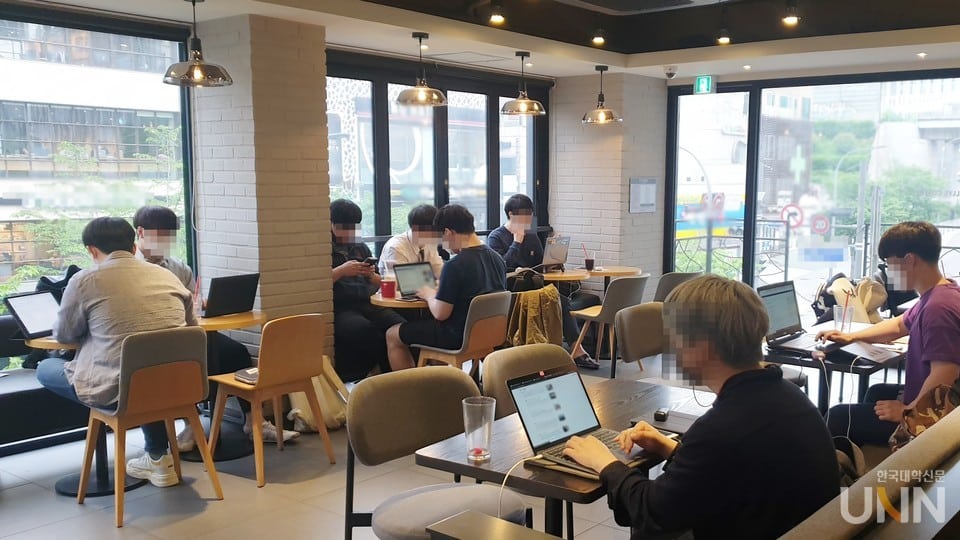 Des étudiants et jeunes travailleurs qui travaillent, étudient sur leurs ordinateurs portables dans un café en Corée du Sud, illustrant le phénomène des Cagongjok (카공족)